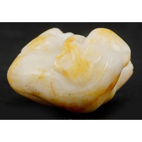 1486 - A Chinese carved celadon and russet jade temple dog, 4cm wide.