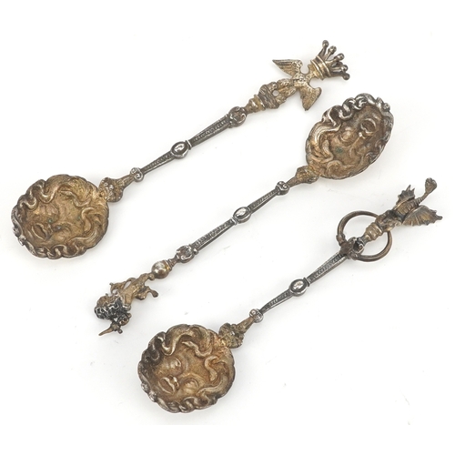 3656 - A set of three silver gilt souvenir spoons with masked bowls and figural finials including a dragon,... 