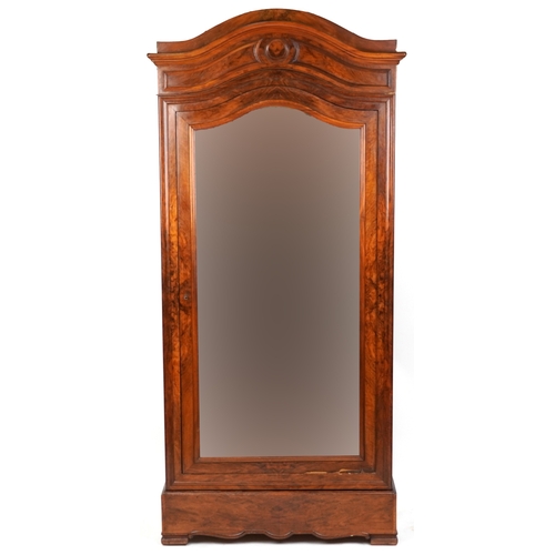 2002 - A 19th century walnut armoire, the arched pediment above a mirrored panel door, the base fitted with... 
