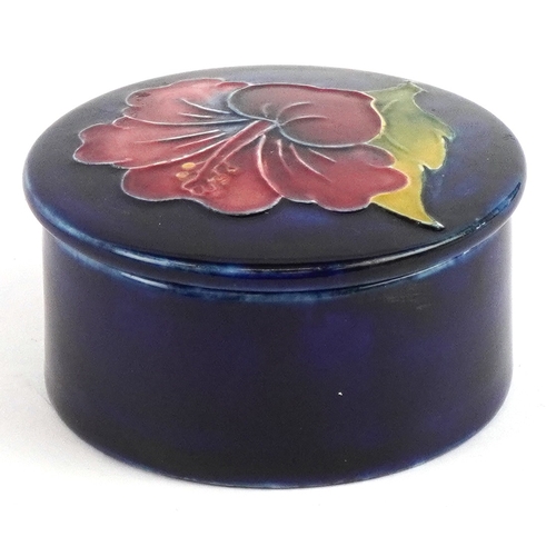 191 - A Moorcroft pottery pot and cover hand painted in the Hibiscus pattern, 7cm in diameter.