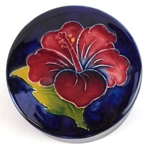 191 - A Moorcroft pottery pot and cover hand painted in the Hibiscus pattern, 7cm in diameter.