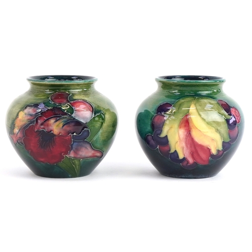 182 - Two Moorcroft pottery squat vases hand painted in the Leaf & Berry and Orchid patterns, 7.5cm high.