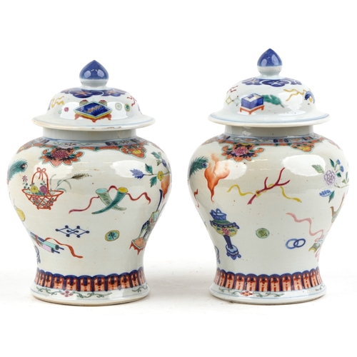 88 - A near pair Chinese porcelain baluster vases and covers, each hand painted with objects amongst a fl... 