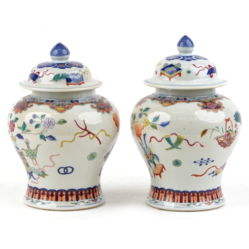 88 - A near pair Chinese porcelain baluster vases and covers, each hand painted with objects amongst a fl... 