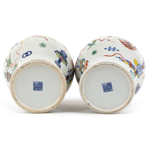 88 - A near pair Chinese porcelain baluster vases and covers, each hand painted with objects amongst a fl... 