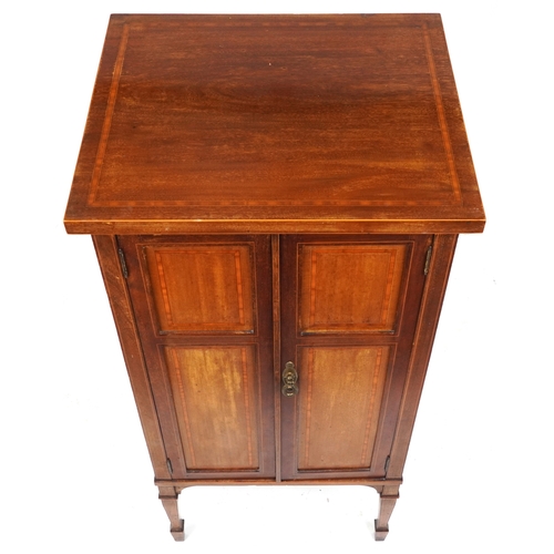 2042 - An Edwardian mahogany music cabinet with satinwood crossbanded decoration, raised on square tapering... 