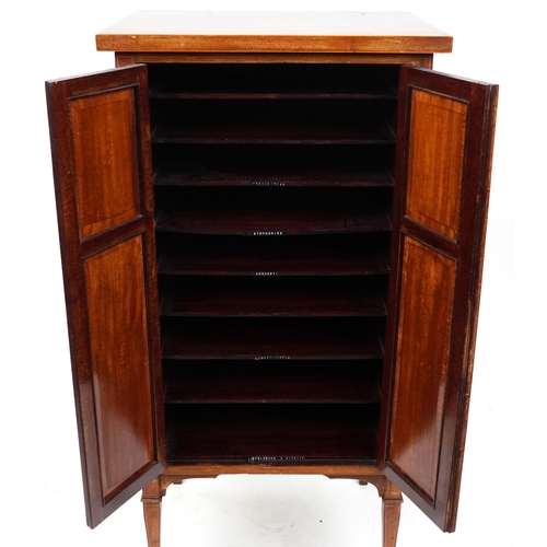 2042 - An Edwardian mahogany music cabinet with satinwood crossbanded decoration, raised on square tapering... 