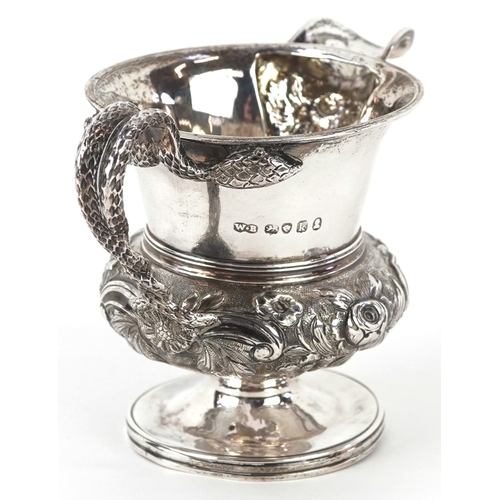 3584 - A George IV silver cream jug having a floral embossed body, entwined serpent handle and a later adde... 