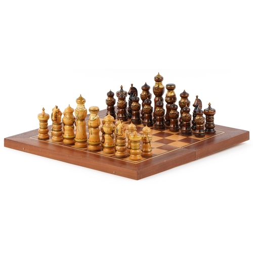732 - A folk art hand painted wooden chess set with folding board, the largest piece 15cm high.