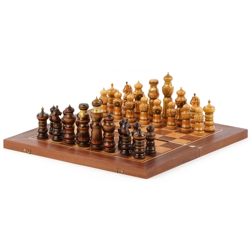 732 - A folk art hand painted wooden chess set with folding board, the largest piece 15cm high.