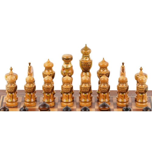732 - A folk art hand painted wooden chess set with folding board, the largest piece 15cm high.