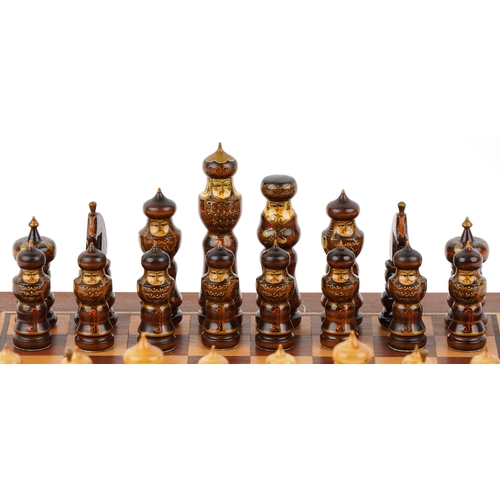 732 - A folk art hand painted wooden chess set with folding board, the largest piece 15cm high.