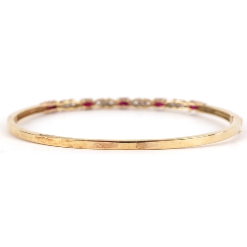 3012 - A 9ct gold ruby and diamond bangle, 6.5cm wide, 7.3g.