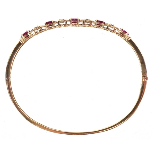 3012 - A 9ct gold ruby and diamond bangle, 6.5cm wide, 7.3g.