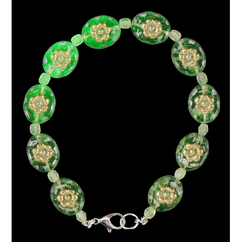 3387 - A uranium glass bead bracelet with floral design, 19cm in length, 14.1g.