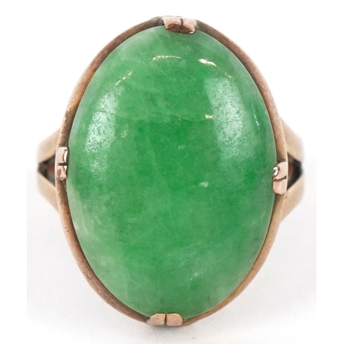 3071 - A Chinese unmarked gold cabochon green stone ring, tests as jade, the stone 2.1cm in length, size M/... 