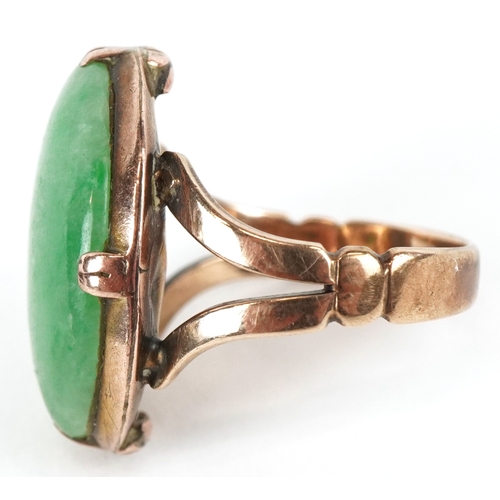 3071 - A Chinese unmarked gold cabochon green stone ring, tests as jade, the stone 2.1cm in length, size M/... 