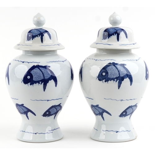 465 - A matched pair of Chinese blue and white porcelain vases and covers hand painted with fish, the larg... 