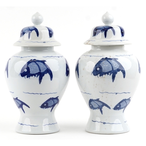 465 - A matched pair of Chinese blue and white porcelain vases and covers hand painted with fish, the larg... 