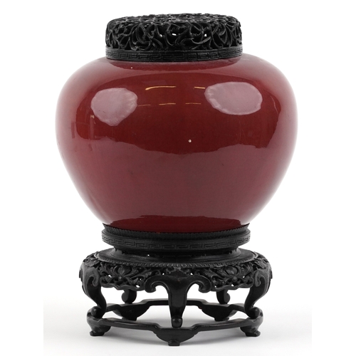 86 - A large Chinese porcelain vase and cover with sang de boeuf glaze, raised on an ebonised carved wood... 