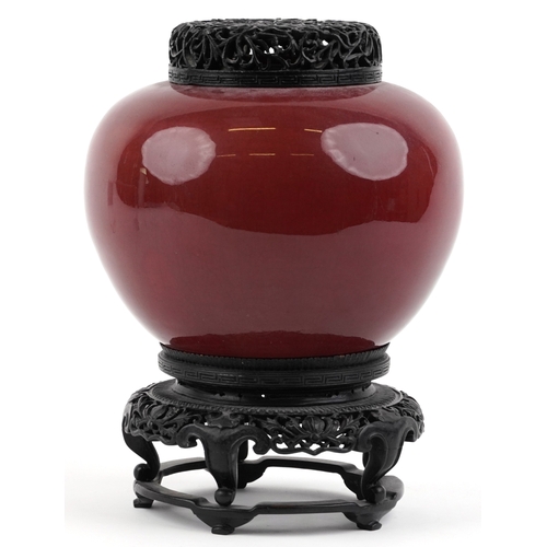 86 - A large Chinese porcelain vase and cover with sang de boeuf glaze, raised on an ebonised carved wood... 
