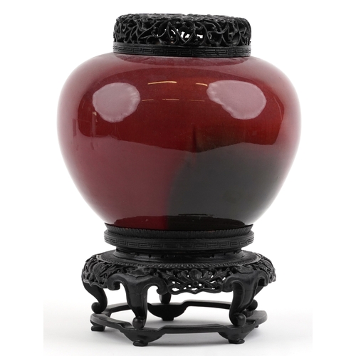 86 - A large Chinese porcelain vase and cover with sang de boeuf glaze, raised on an ebonised carved wood... 
