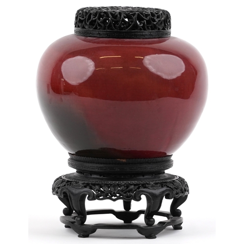 86 - A large Chinese porcelain vase and cover with sang de boeuf glaze, raised on an ebonised carved wood... 