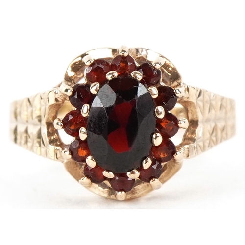 3189 - A 9ct gold two tier garnet cluster ring with engraved shoulders, size M, 2.7g.