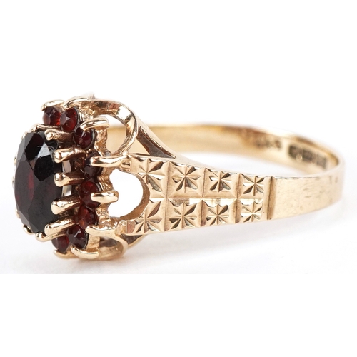3189 - A 9ct gold two tier garnet cluster ring with engraved shoulders, size M, 2.7g.