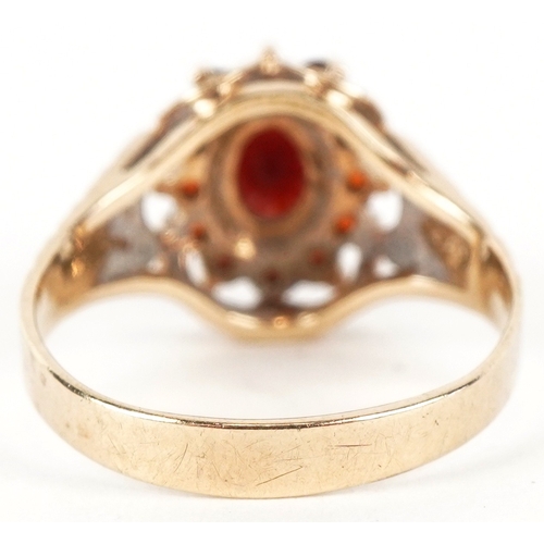 3189 - A 9ct gold two tier garnet cluster ring with engraved shoulders, size M, 2.7g.