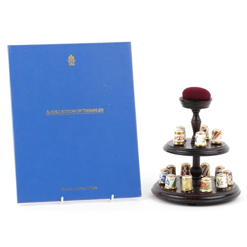 669 - A set of fifteen Royal Crown Derby porcelain thimbles with hardback book and two tier display stand,... 