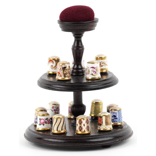 669 - A set of fifteen Royal Crown Derby porcelain thimbles with hardback book and two tier display stand,... 