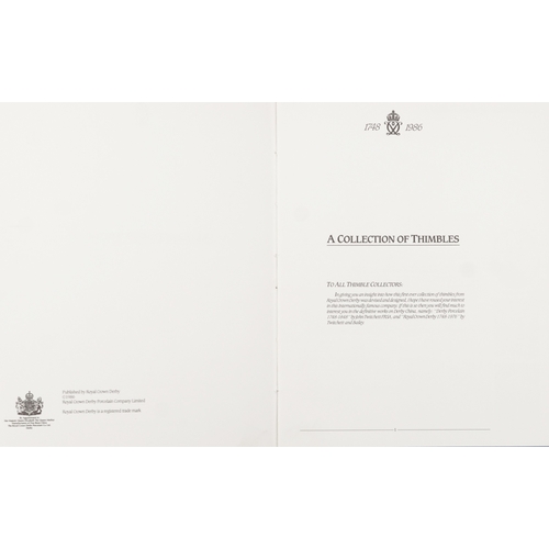 669 - A set of fifteen Royal Crown Derby porcelain thimbles with hardback book and two tier display stand,... 