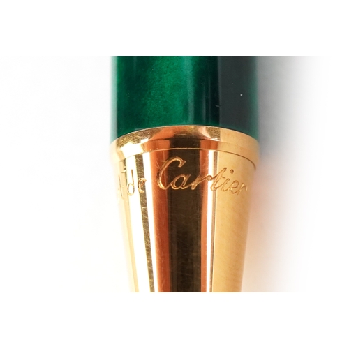 55 - Cartier, a malachite design and gold plated ballpoint pen numbered B85336, with box and paperwork.