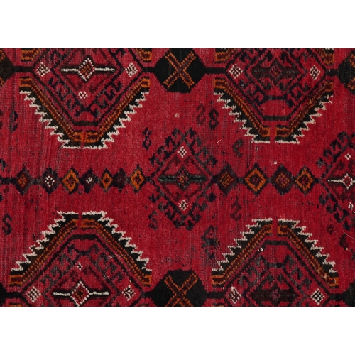 2223 - An Afghan rug, 20th century, the red field with two rows of stylized medallions within a complementa... 