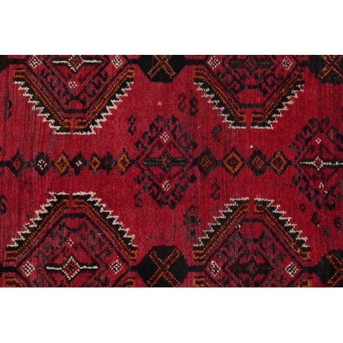 2223 - An Afghan rug, 20th century, the red field with two rows of stylized medallions within a complementa... 