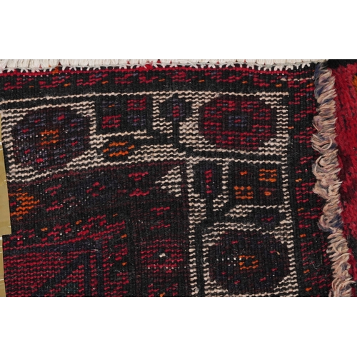 2223 - An Afghan rug, 20th century, the red field with two rows of stylized medallions within a complementa... 
