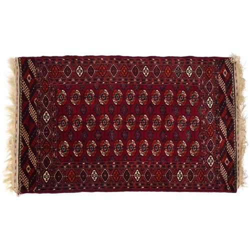 2207 - A Turkmen Tekke rug, late 20th century, the red field with three central rows of guls within a compl... 