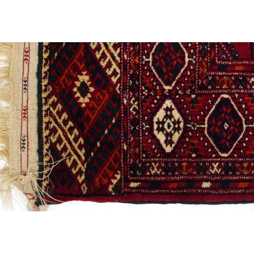 2207 - A Turkmen Tekke rug, late 20th century, the red field with three central rows of guls within a compl... 