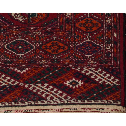 2207 - A Turkmen Tekke rug, late 20th century, the red field with three central rows of guls within a compl... 