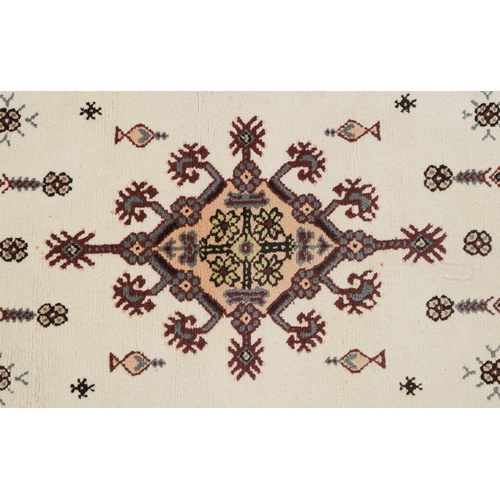 2210 - A Tunisian wool rug, modern, the white field with a central stylized medallion within a complementar... 