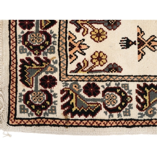 2210 - A Tunisian wool rug, modern, the white field with a central stylized medallion within a complementar... 