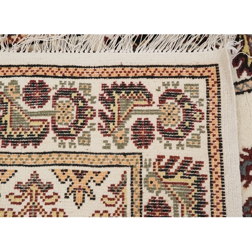 2210 - A Tunisian wool rug, modern, the white field with a central stylized medallion within a complementar... 