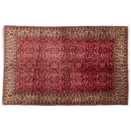 2208 - A Persian rug, 20th century, the red field with an overall scrolling flower head design within a com... 