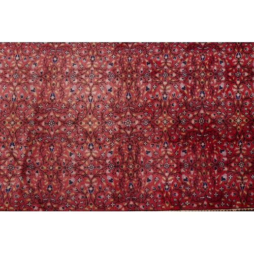 2208 - A Persian rug, 20th century, the red field with an overall scrolling flower head design within a com... 