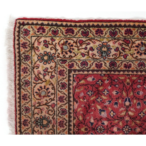 2208 - A Persian rug, 20th century, the red field with an overall scrolling flower head design within a com... 