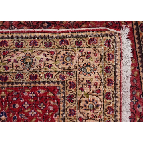 2208 - A Persian rug, 20th century, the red field with an overall scrolling flower head design within a com... 