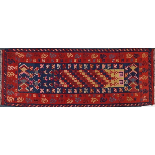 2214 - A Kilim runner, 20th century, the red field with a central section decorated with animals, within a ... 
