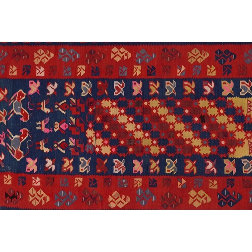 2214 - A Kilim runner, 20th century, the red field with a central section decorated with animals, within a ... 