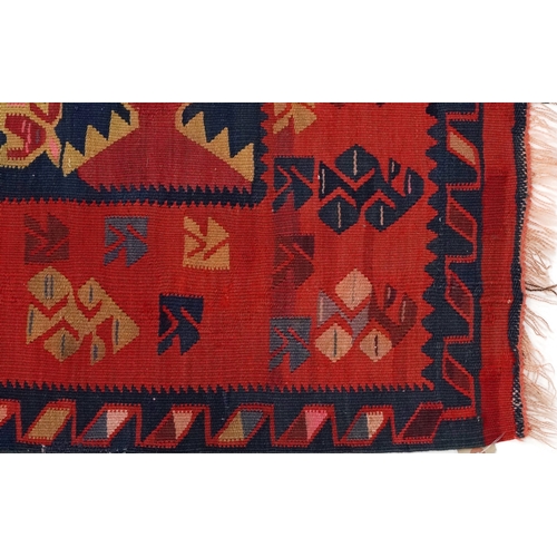 2214 - A Kilim runner, 20th century, the red field with a central section decorated with animals, within a ... 